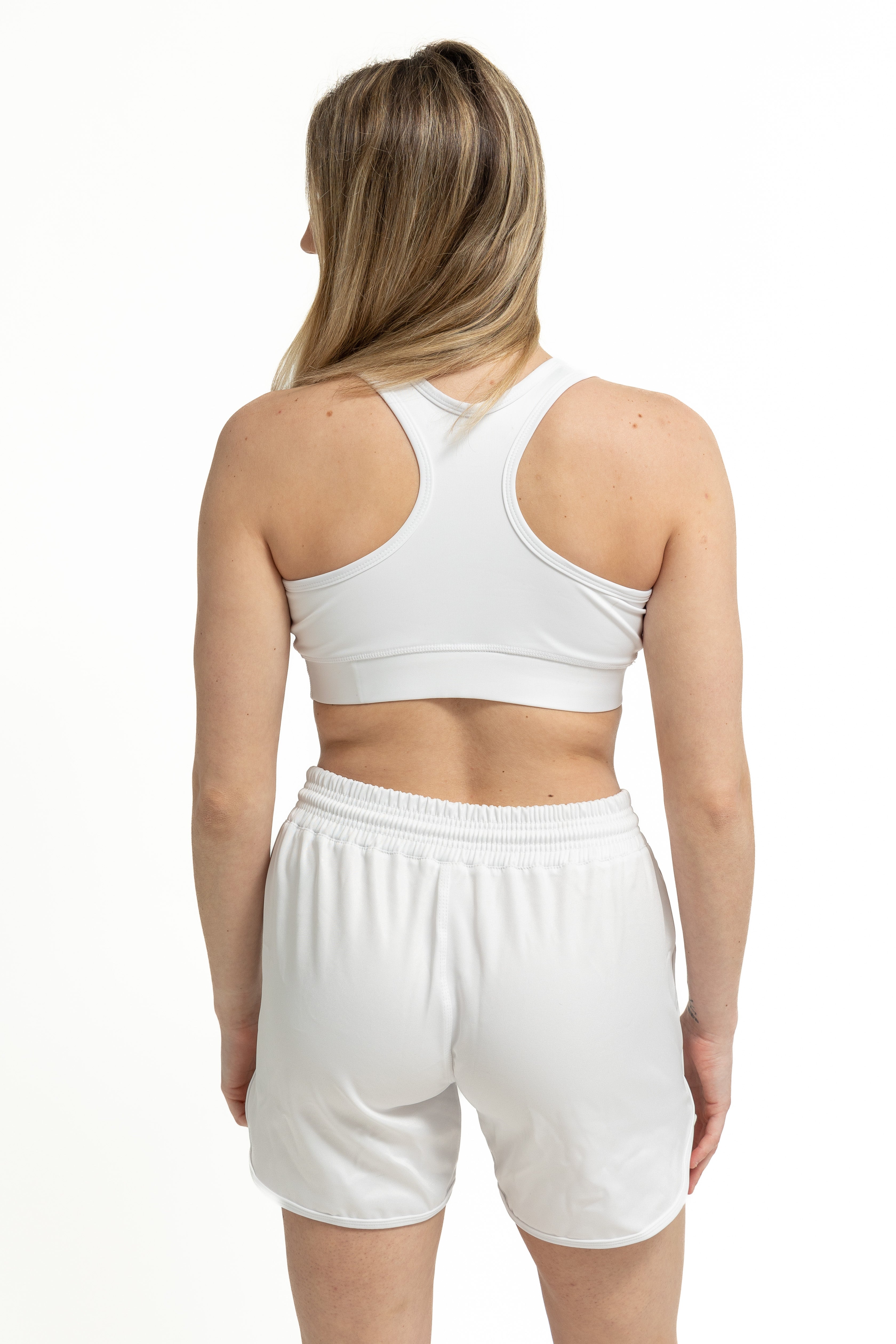Girl modeling a white high-compression sports bra and white athletic shorts