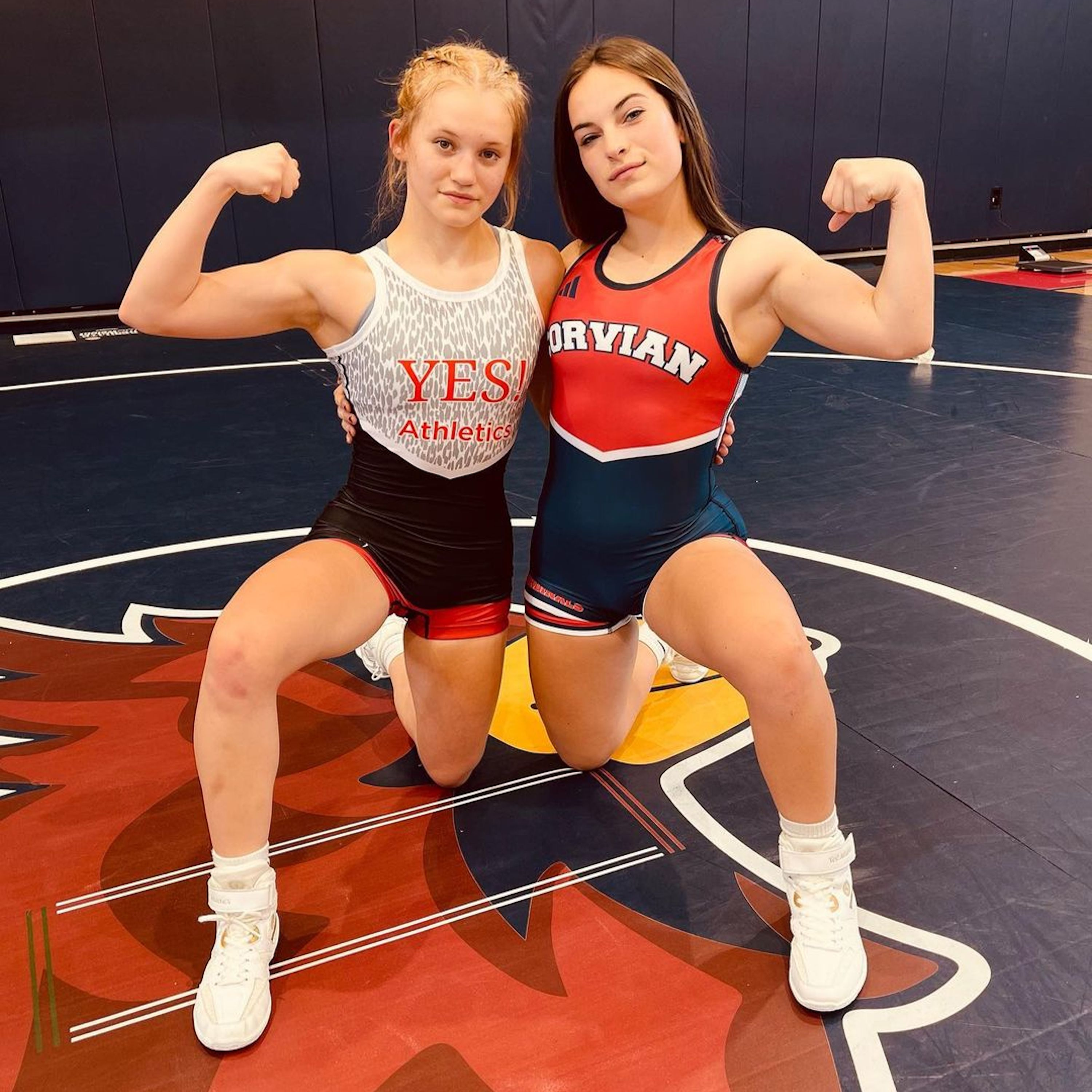 Girl athletes in wrestling gear flexing muscles
